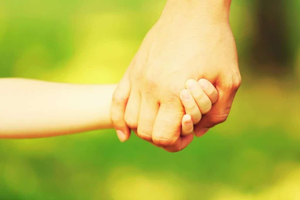 Adult holding child's hand to demonstrate safeguarding children