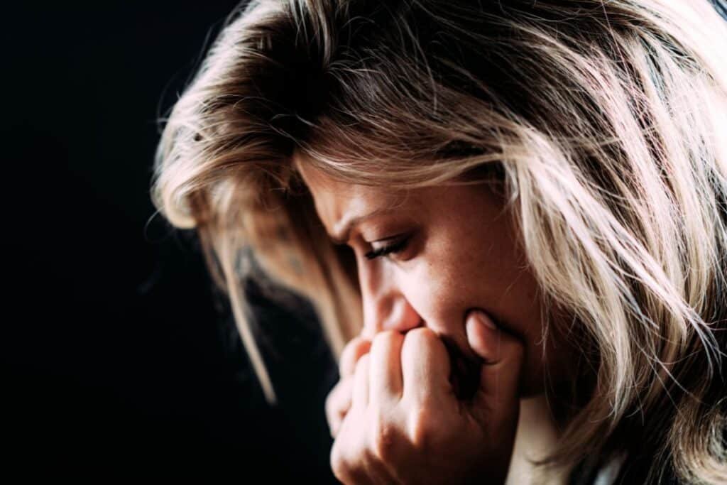 Blonde woman looking upset with her head in her hands as she copes with PTSD triggers