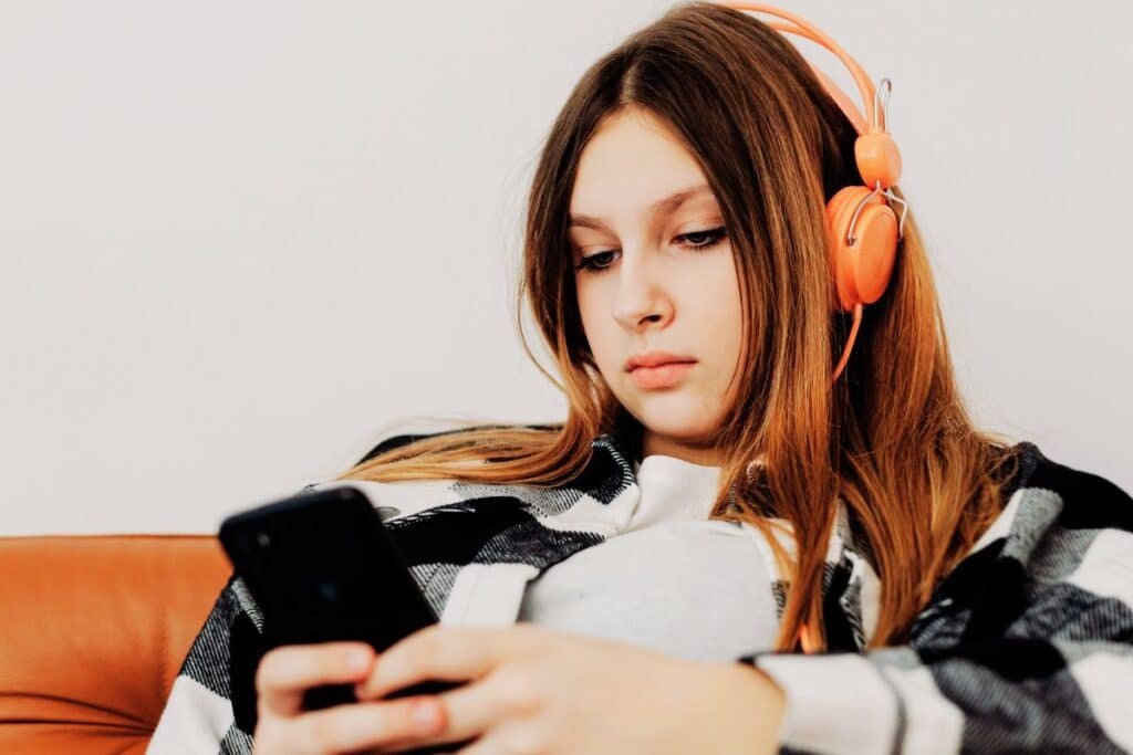 Teenager wearing orange headphones on mobile phone