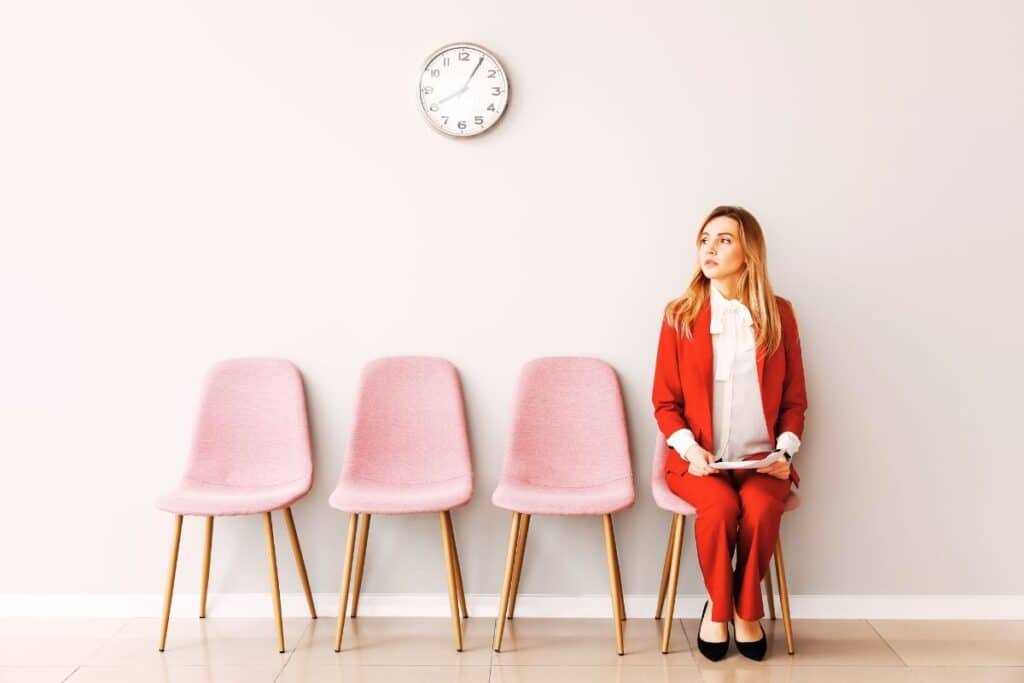 woman wearing red waiting on a pink chair