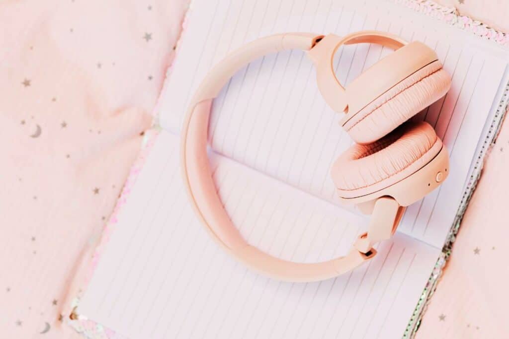 pink headphones on notebook playing Songs for Processing Trauma