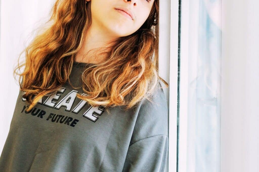 teenage girl looking out of the window and looking worried