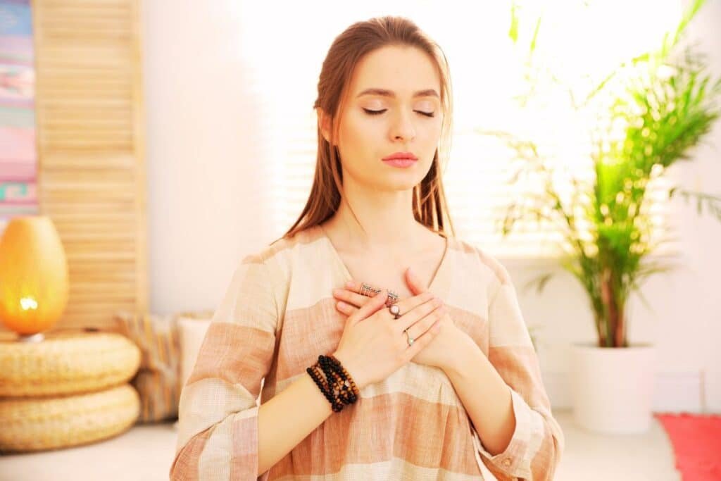 woman with hands on her chest whilst breathing and meditating, perhaps after experiencing a panic attack