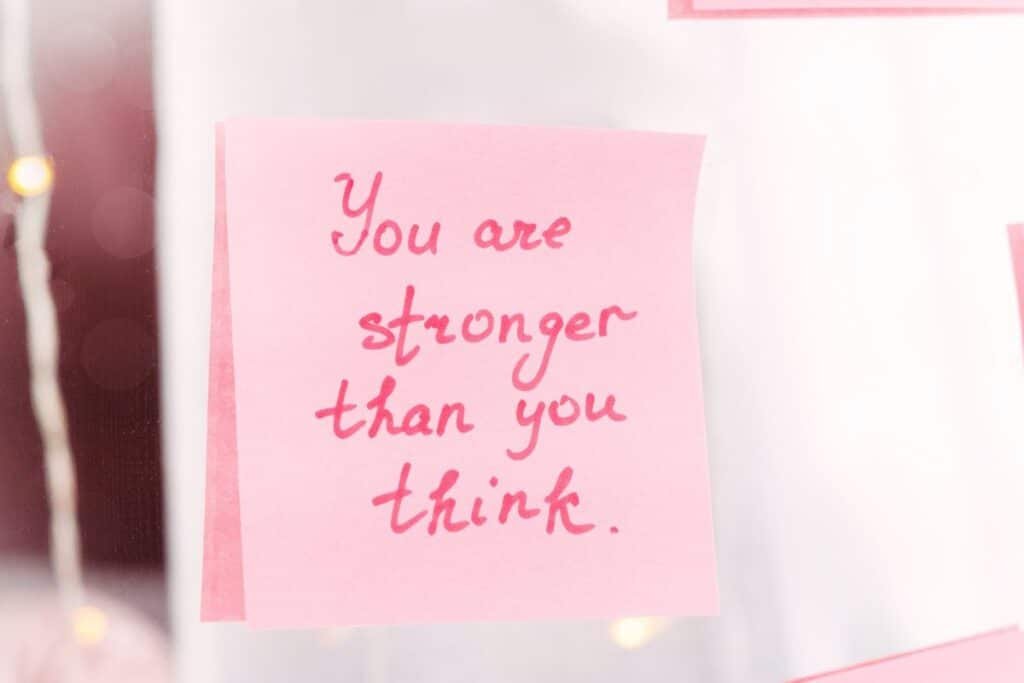 'you are stronger than you think' written on a pink post-it note and stuck to a mirror