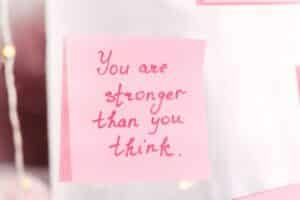 'you are stronger than you think' written on a pink post-it note and stuck to a mirror